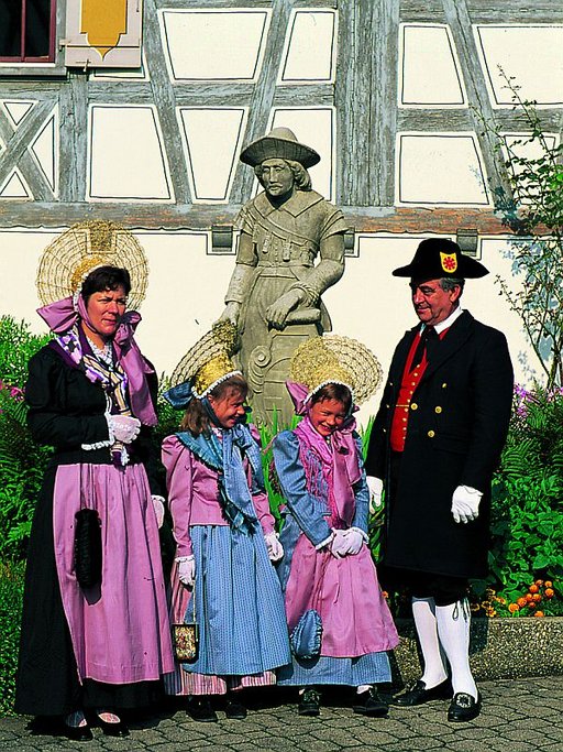 Trachtenfamilie mit Sandsteinfigur